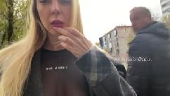 A girl shows her breasts while walking in public in the city